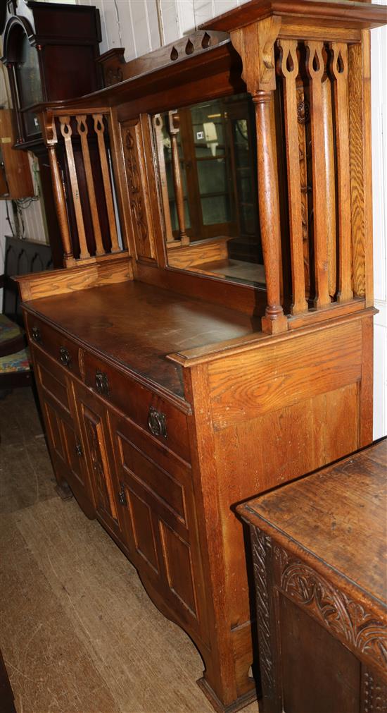 An Arts & Crafts carved oak sideboard with raised mirrored back, W. 5ft 8in. D. 1ft 11in. H. 6ft 4in.